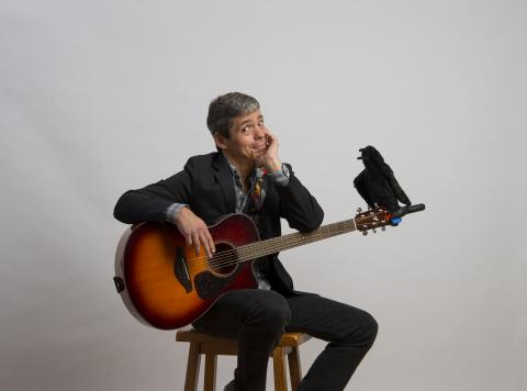 Allan Wolf holding a guitar with a raven on the neck of the guitar