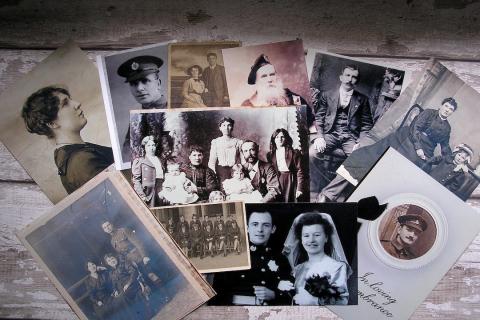 11 black and white photos of people from the past on a wooden table.