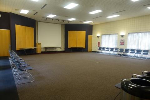 Meeting room with 20 chairs along the walls. There is a table set up in front.