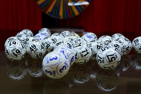 28 bingo balls on a black table with a colorful wheel in the background.