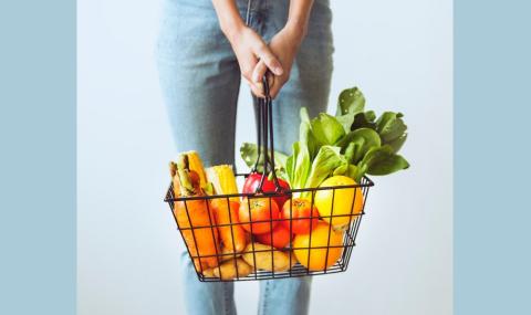 person holding a wire basket full of vegetables