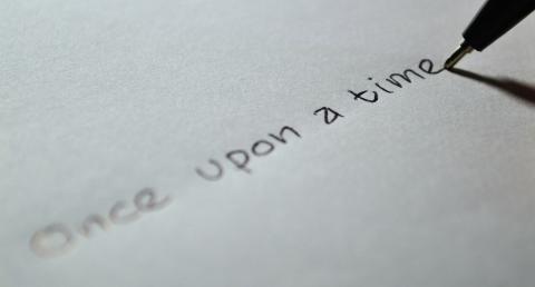 A white piece of paper with a pen writing the words, "Once upon a time."