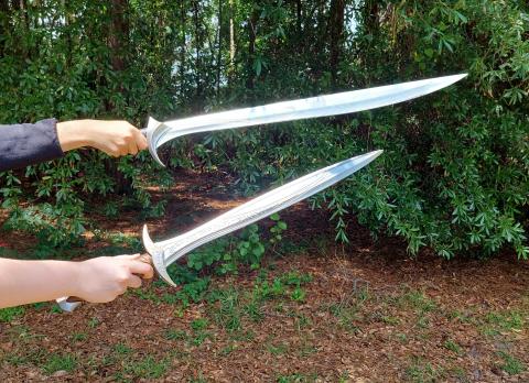 two elvish style swords being held in front of trees