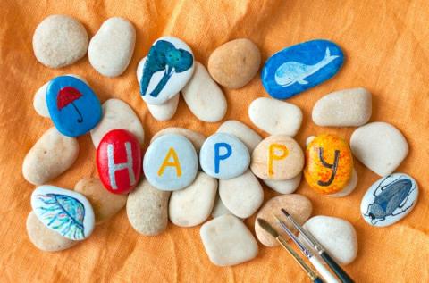 five painted rocks spelling out 'happy" and rocks painted with various animals around them