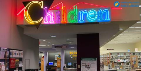 Image of the entrance to the children's room at Spring Lake Community Library. There is a neon sign in different colors spelling out "Children" above the entrance.