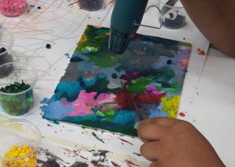 Crayons being melted with a hair dryer onto a canvas.