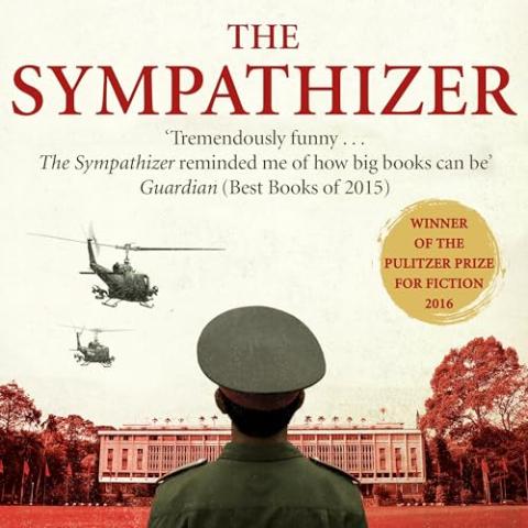 Cover of "The Sympathizer" that is showing the back of a man dressed in a military uniform looking at two helicopters flying over a large building with trees on both sides of the building.
