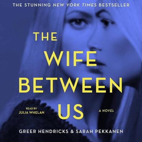 Book cover for "The Wife Between Us", featuring a blue-tinted close-up of a woman’s doubled, blurred face, with the title in large yellow text and author names Greer Hendricks & Sarah Pekkanen.