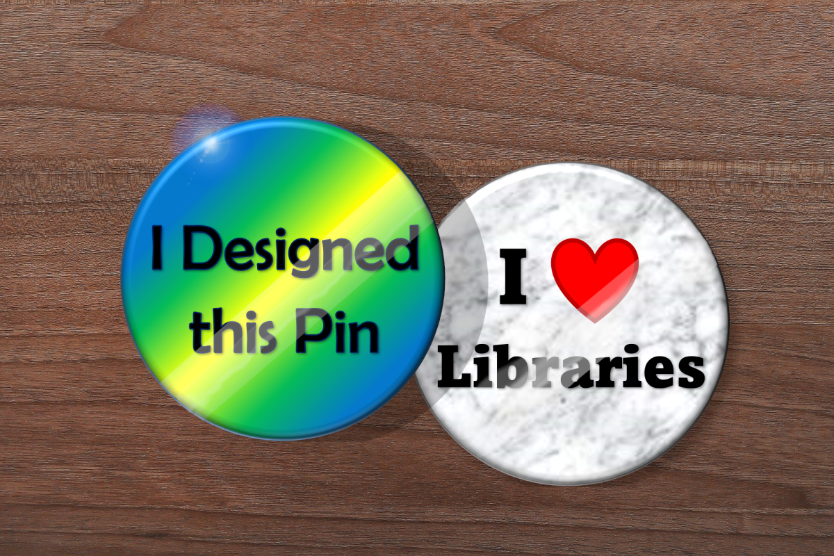 One button pin saying I designed this pin and another saying I heart libraries