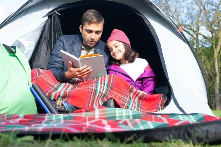 man reading to girl in tent