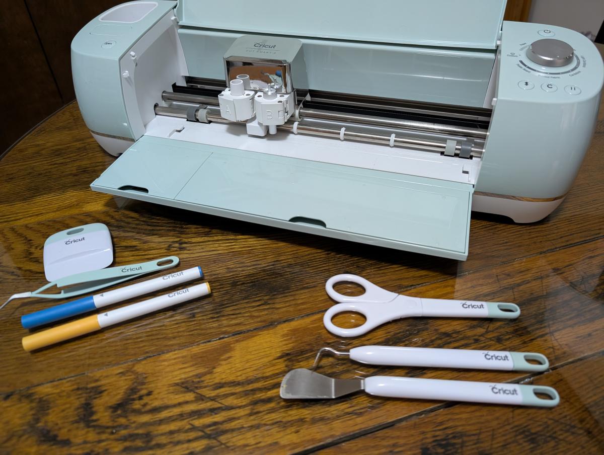 Cricut cutting machine and accessories on a brown table.