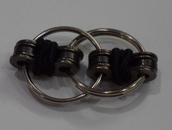 Image of a fidget made with two black bike chain links and two silver key rings connected together.